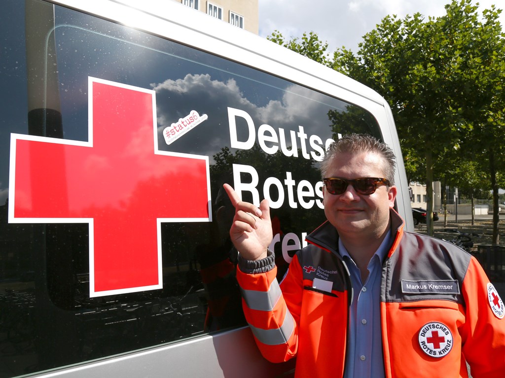 Initiator der Kampagne #status6, Markus Kremser, steht vor dem DRK Einsatzwagen, der mit einem #status6-Aufkleber ausgestattet ist. 